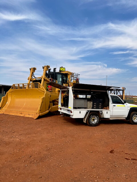 CAT D9 bulldozer and an Equipmech service ute on a red dirt site under blue skies, prepared for heavy equipment maintenance.