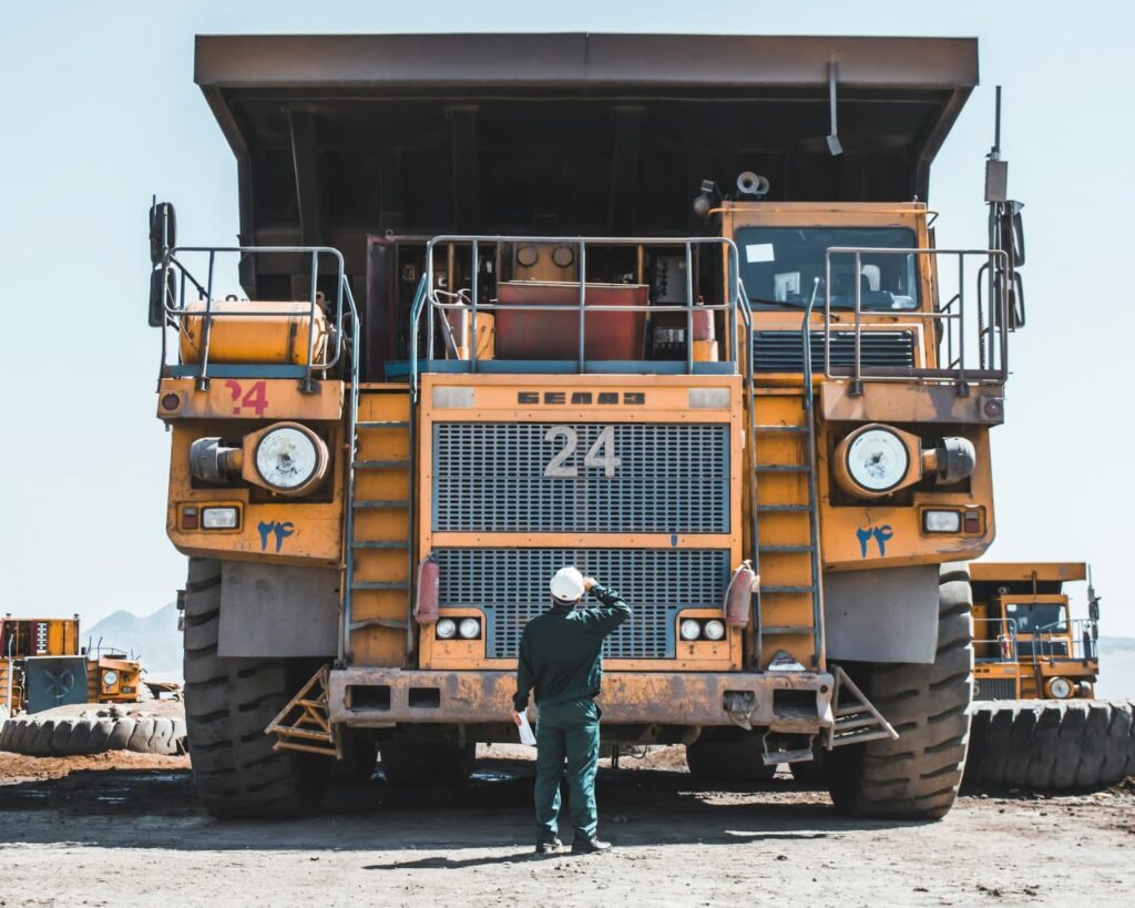 A front view of a dumper with a worker looking in front of it.