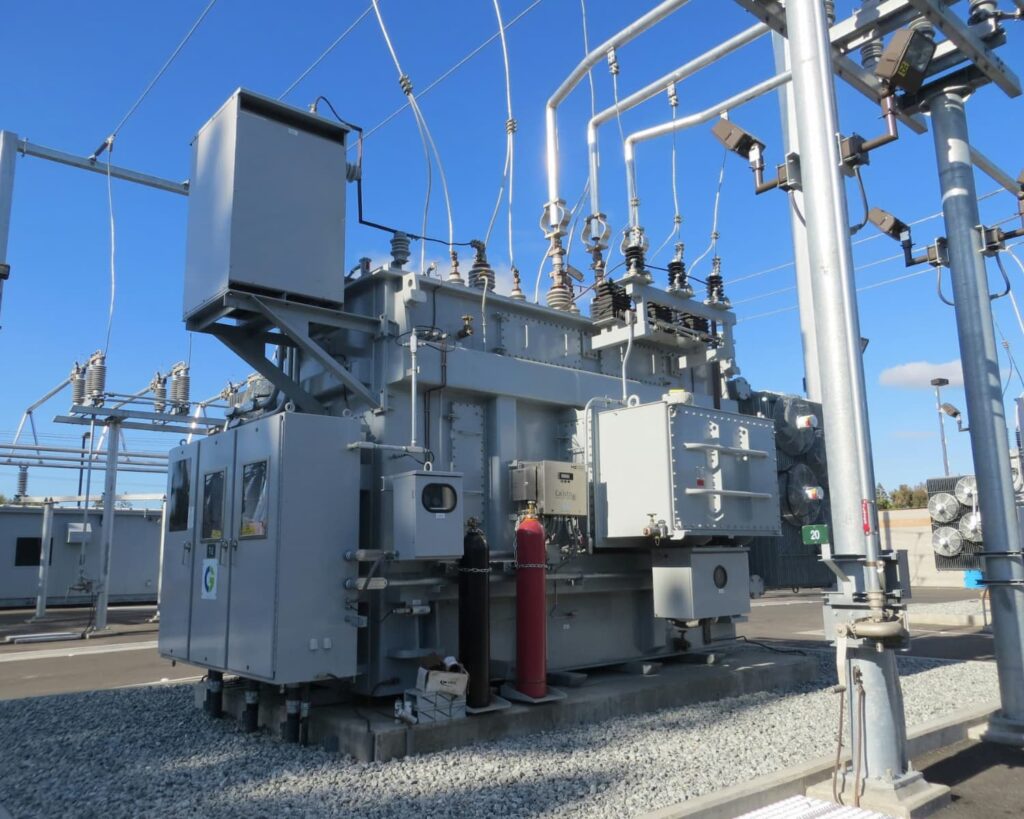 A white power generator stationed under a clear blue sky.